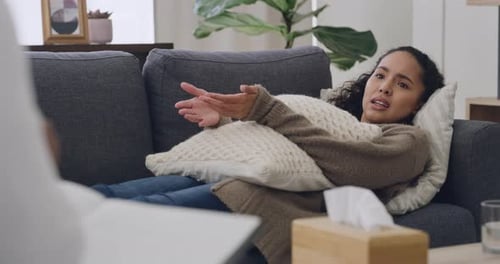 Young woman in therapy session lying on a sofa with a psychologist