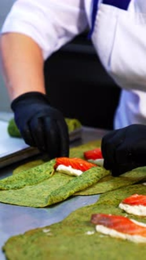Unusual green crepes are rolled with cheese and salmon fish.