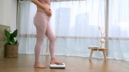 Big belly of pregnant woman standing on weight scale check baby development and measuring weight gai
