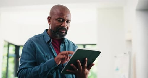 Creative, black man and reading with tablet in office for research, proofreading and update draft