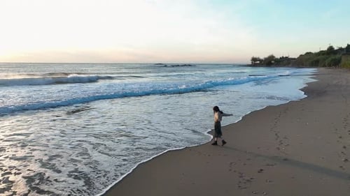 A Beautiful Girl Walks on the Beach of the Mediterranean Sea and Enjoys a Beautiful Sunset