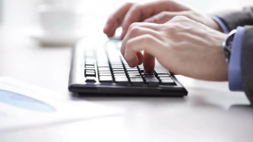 Businessman typing on computer keyboard and drinking coffee in office workplace