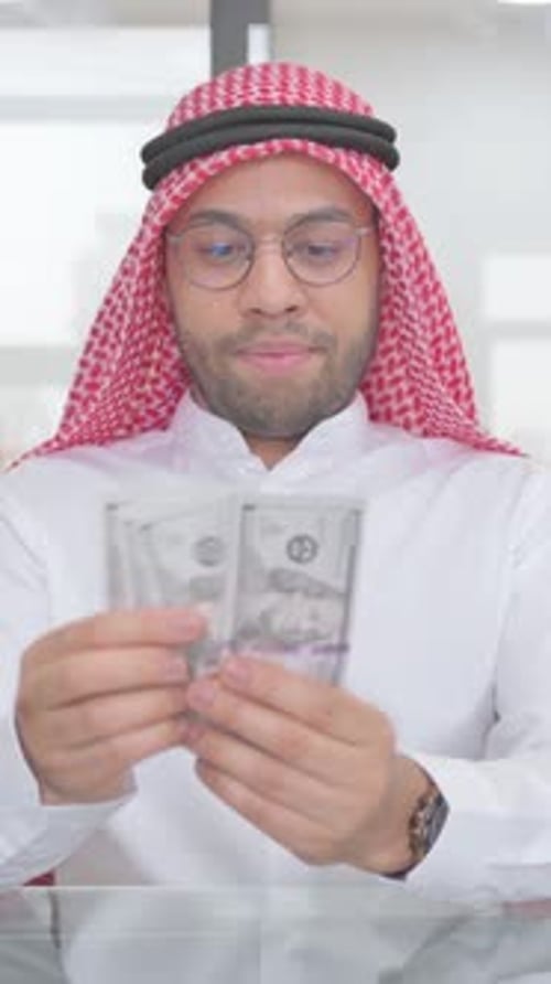 Man in Keffiyeh Counts Stack of Dollar Bills