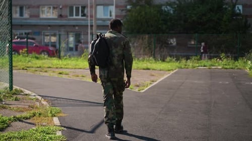 Man with backpack walks on asphalt path