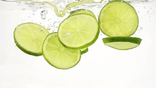 Slices of lime fall into clear water