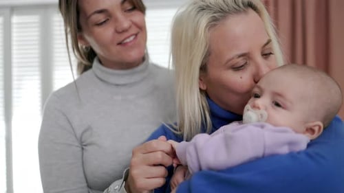 Gay lesbian couple mothers and newborn baby enjoying together at home - Lgbt family concept