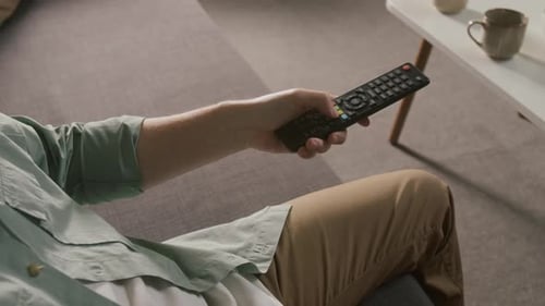 Hand des Fernsehers, der beim Wählen des Fernsehsenders die Fernbedienungstasten drückt