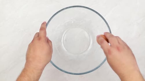 Cracking eggs and mixing them in the bowl.