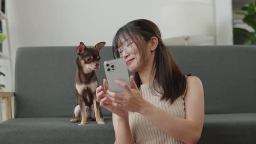 Woman Using Phone with Dog on Couch