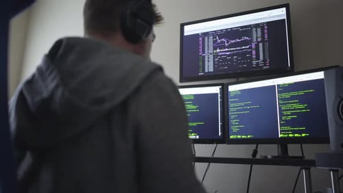 Hacker mit drei Computerbildschirmen beim Tippen
