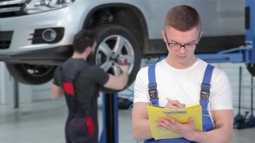 Le mécanicien écrit quelque chose dans le carnet de route jaune