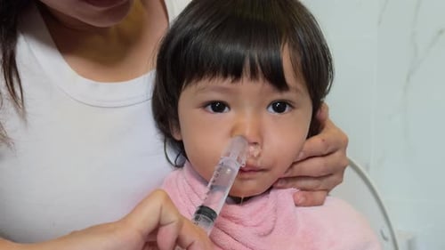 slow-motion of mother making nasal wash for toddler with a syringe and saline. cleaning baby nose