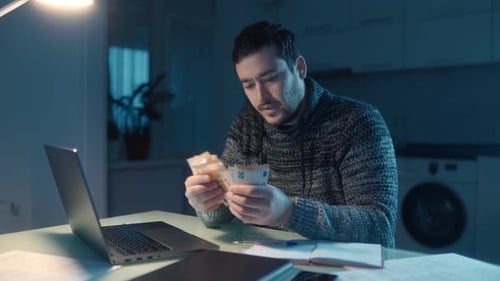 Man counting money at desk at night