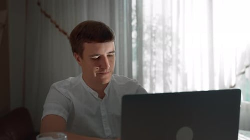 Young Adult Typing on Laptop at Home
