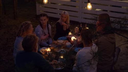 Friends Gather Around Table in Rural Setting at Night