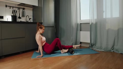 Woman Using Foam Roller for Leg Exercise at Home