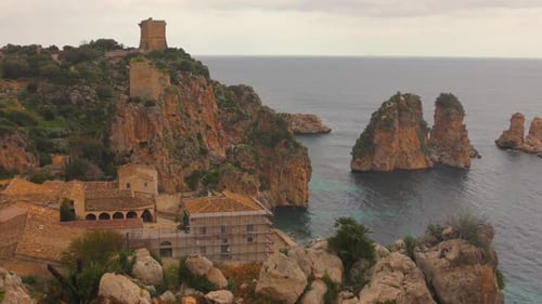Coastal view of Sicily featuring rugged cliffs and the Mediterranean sea with ancient architecture