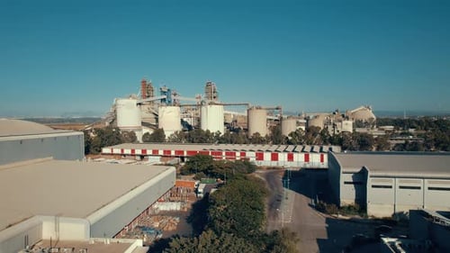 Aerial shot of a huge cement factory, an innovative industrial area with lots of hangars and trucks,