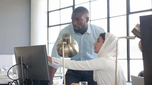 Colaborando no projeto, colegas discutindo o trabalho no computador em um escritório moderno