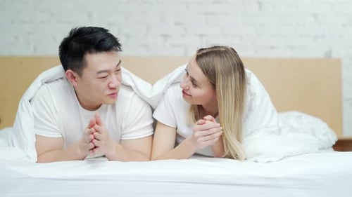 Couple in Bed Talking and Laughing Under Blanket