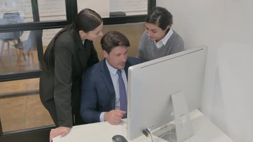 Team Collaborating Around Computer in Modern Office