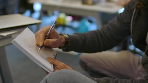 Adult Sketching in Notepad at Modern Office