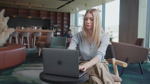 In Restaurant Portrait Attractive Blond Young Woman Using and Typing Laptop in a Cafe Sitting