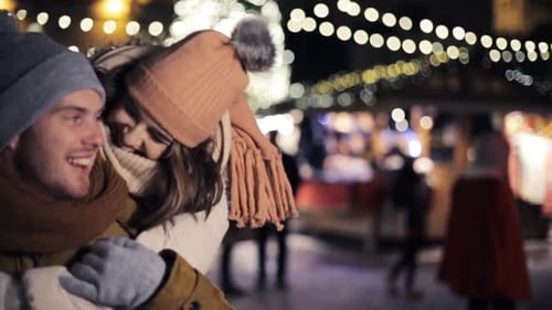 Affectionate couple piggyback ride on European Christmas market