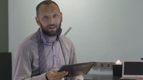 Young Businessman with Tablet Explaining, Talking to Camera in Hotel Room Advice