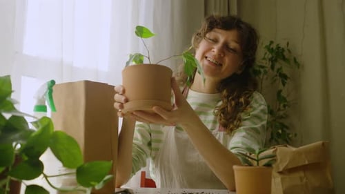 Woman Gardener Tending Potted Plant Surrounded By Gardening Supplies Creating Warm Domestic Scene