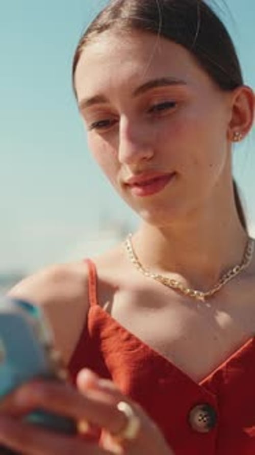 Close-up portrait pretty woman sitting in the seaport uses a mobile phone