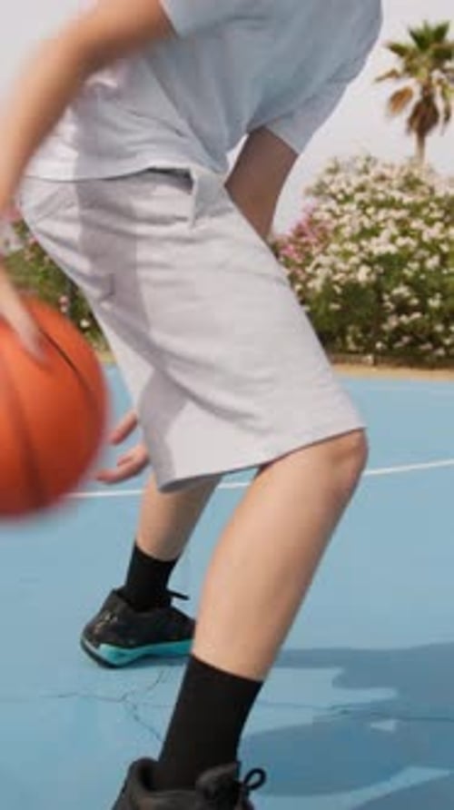 Young Athlete Dribbles Under His Legs On The Basketball Court