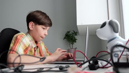Young Student Programming a Robot Dog with Laptop