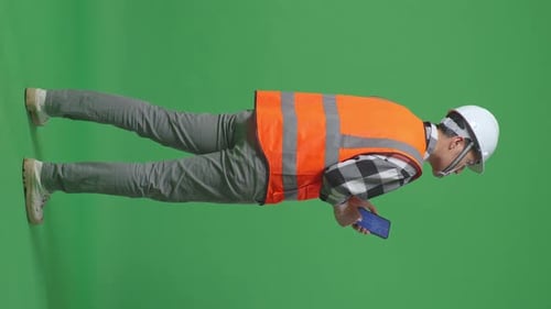 Back View Of Male Engineer Looking At The Wind Turbine Blueprint On Smartphone On Green Screen