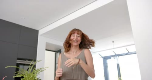 Auburn Haired Woman Dances in Modern Kitchen