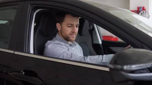 Young Man Smiling in New Car at Dealership