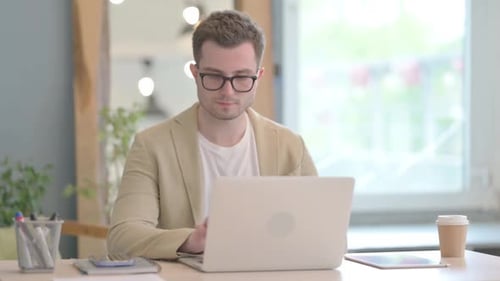Man Working at Laptop Reacts with Joy