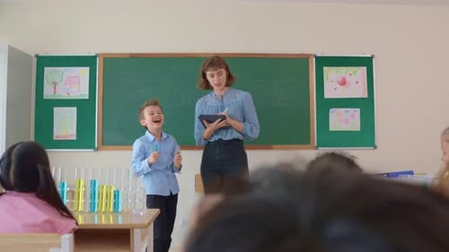 Adorable student learn with teacher in classroom at elementary school.