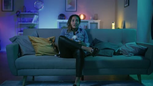 Beautiful Excited Young Black Gamer Girl Sitting on a Couch and Playing Video Games on a Console. S