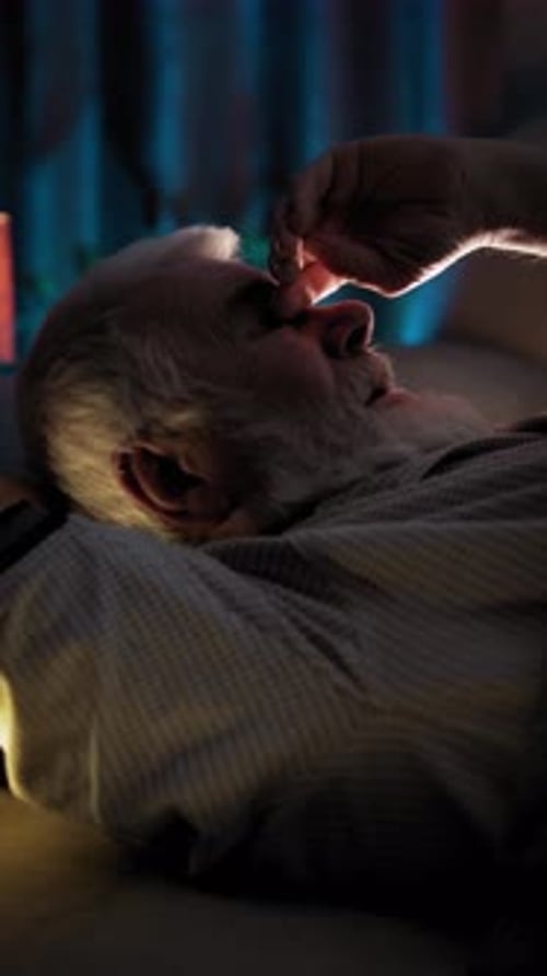 Sleeping Elderly Man in Bed Puts His Hand More Comfortably Under His Head
