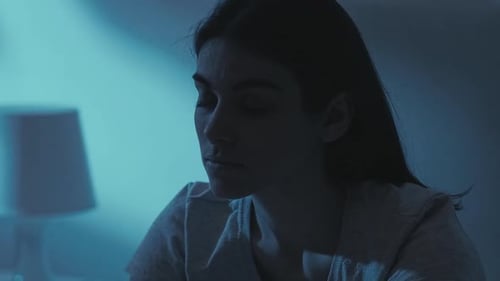 Sad Woman Sitting in Dark Bedroom at Night