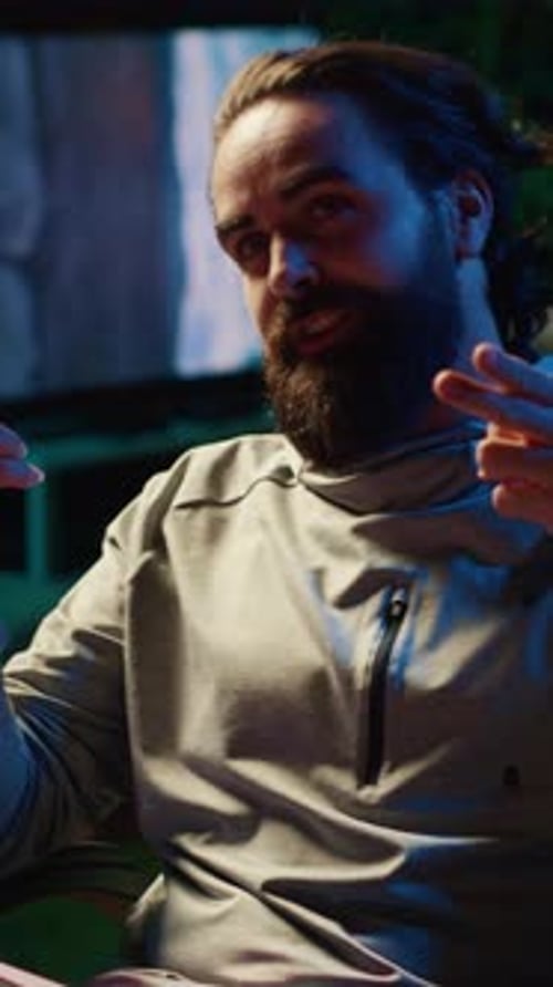 Man Gesturing and Talking Indoors at Night