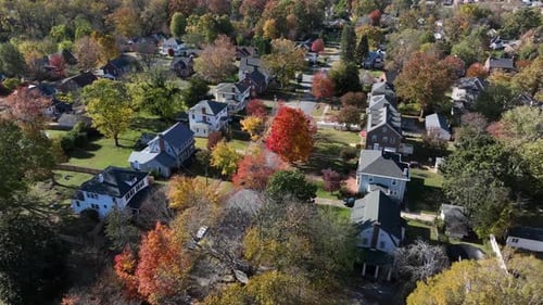 Aerial view of an American suburb in peak autumn with houses, winding streets and colorful foliage.