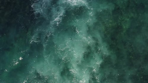 White Ocean Waves flowing over reef in clear Blue Water shot with Aerial Drone