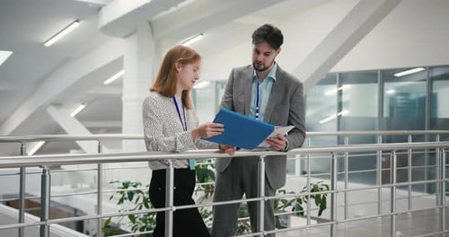 Business Professionals Review Paperwork in Office Corridor