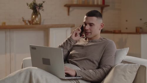 Young Adult Uses Laptop and Cellphone at Home