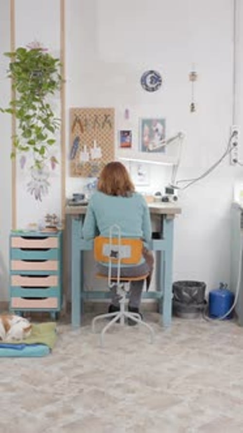 Back View Of A Girl Jeweler Working Inside The Studio Domestic Dog Lying At The Floor Dolly Shot