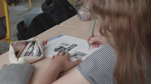 Girl Completing Worksheet at Desk in Classroom