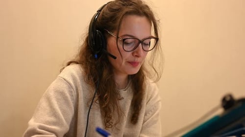 Woman Working with Headset, Taking Notes Indoors