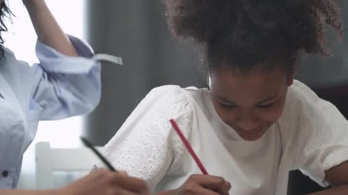 Pretty Darkskinned Girl Doing Homework Sitting at the Table at Home with Her Mom Draw Lessons